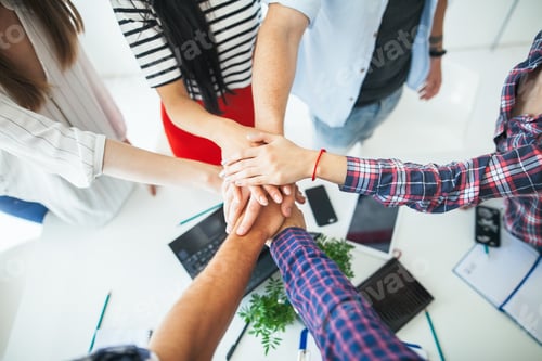 Preview: Top view of young business people putting their hands together