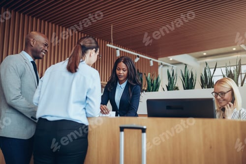 Preview: Smiling guests talking with a hotel concierge during check in