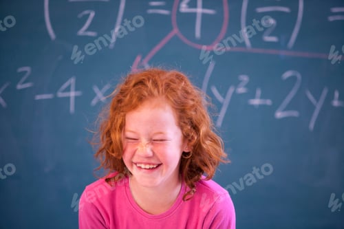 Preview: Portrait of cute primary schoolgirl giggling in classroom