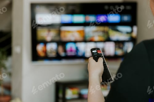 Preview: Hand holding remote control pointing to TV. Person watching smart television