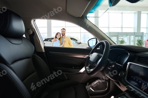 Preview: Happy woman and man looking at camera in car center
