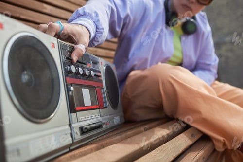 Preview: Close up of girl pressing button on old school boombox playing music urban
