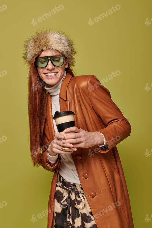 Preview: Young man with long red hair enjoys a coffee while wearing stylish winter attire indoors