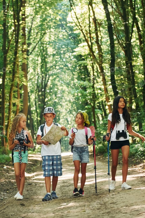 Preview: With map. Kids strolling in the forest with travel equipment