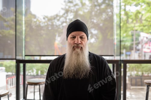 Preview: Portrait of mature man with long gray beard sitting and thinking
