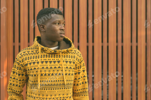Preview: Close up of young black African man thinking while looking at distance against wooden gate