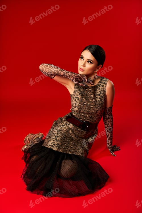 Preview: Fashionable Woman Posing in Leopard Print Dress on Red Background