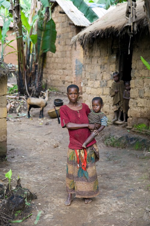 Preview: Young woman carrying a child in a rural village setting.