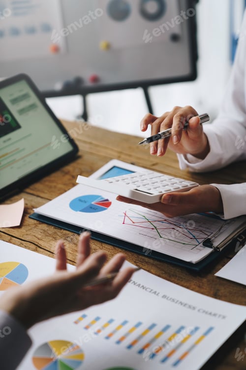 Preview: Financial analysts analyze business financial reports on digital tablets during conversations at cor