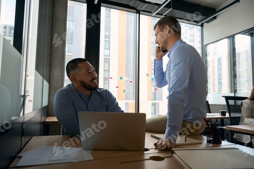 Preview: Cheerful company employee and his colleague in workplace