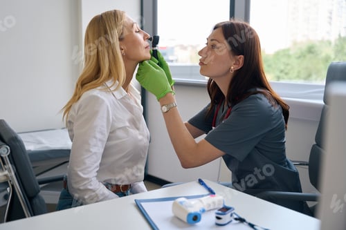 Preview: Experienced otolaryngologist examining nasal cavity of adult woman