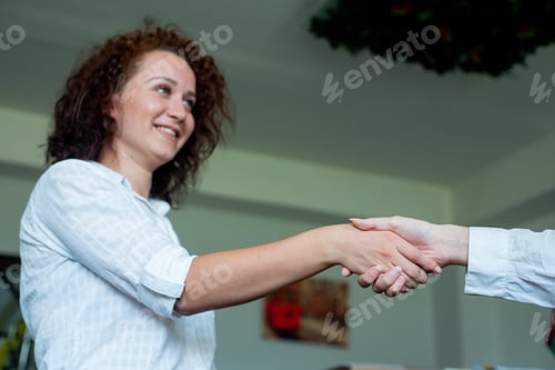 Preview: young woman office worker smiling friendly shaking hands with coworker standing on office