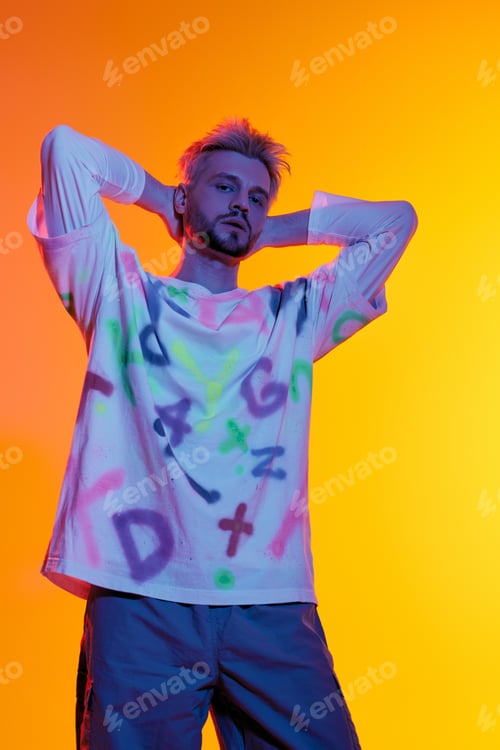 Vista previa: Stylish young man poses confidently against a vibrant orange backdrop