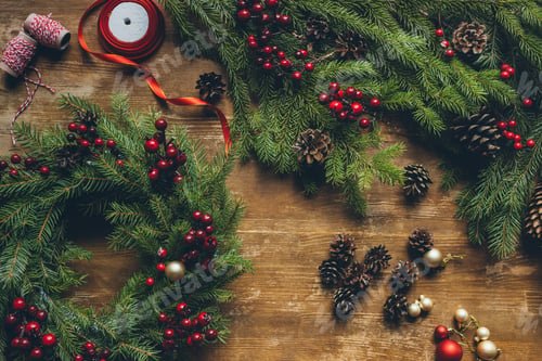 Preview: top view of Christmas wreath with fir, decorative berries and pine cones on wooden tabletop