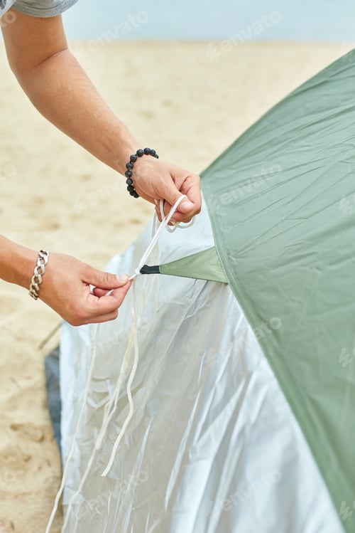 Preview: Young male tourist puts a green tent in the beach coast . The man sets up a camp on a hike
