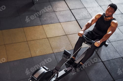 Preview: Strong african american man in sportive clothes have workout day in the gym and using equipment