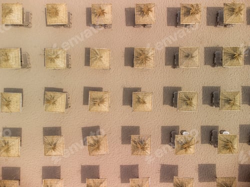 Preview: Aerial view of an amazing empty sand beach with straw beach umbrellas and turquoise clear water.