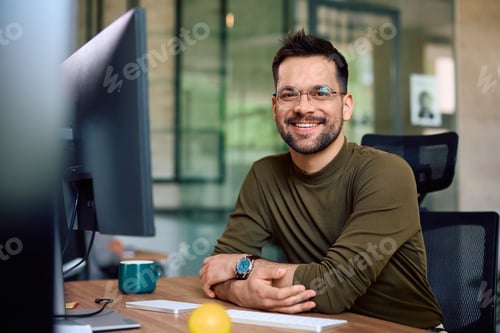 Preview: Happy male entrepreneur at his office desk looking at camera.