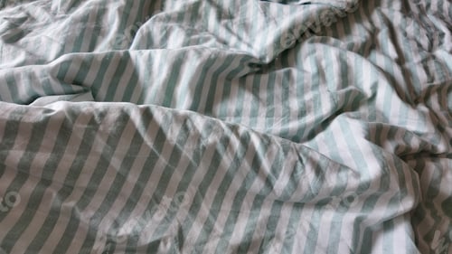 Preview: Bed sheets with stripes on a messy bed