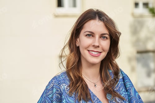 Preview: Portrait of a woman smiling at the camera while standing outdoors on the street.