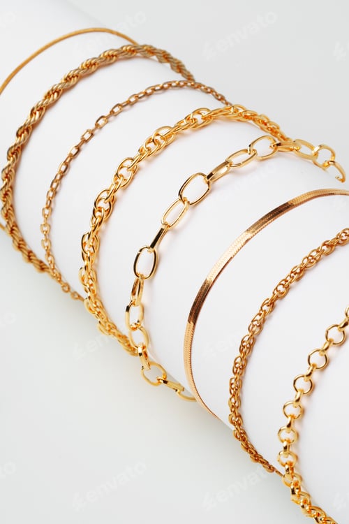 Preview: Set of golden bracelets on display on white background