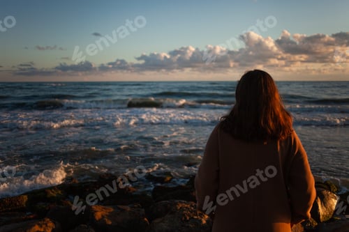 Preview: Female walks shoreline as sun dips.