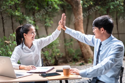 Preview: Young business woman and businessman giving hand high five after job well done