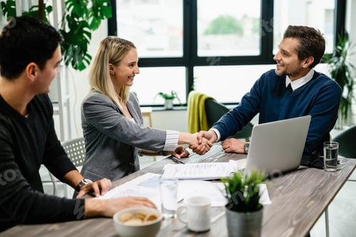 Preview: Happy real estate agent greeting a young couple in the office.
