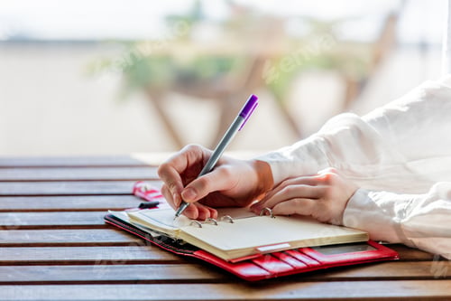 Preview: hand with pen writing something in to a notebook
