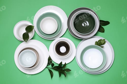 Preview: Different dishware and leaves on green background, flat lay
