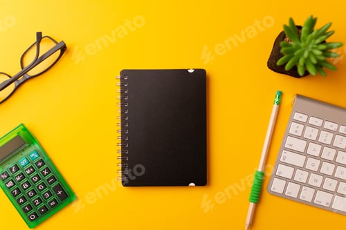 Preview: Top view of a journal, calculator, a pencil, keyboard, and a plant on a yellow background