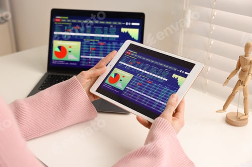 Preview: Stock exchange. Woman analysing financial market on tablet at white table indoors, closeup