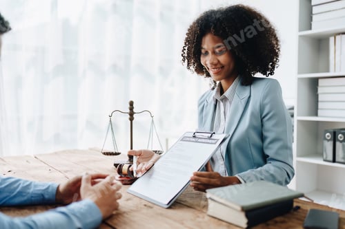 Preview: Young African American lawyer studying a case for a client and signing a legal contract to fight her