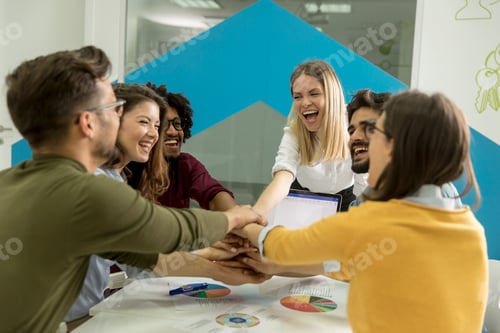 Preview: Team people stacking hands together over table engaged in teambuilding