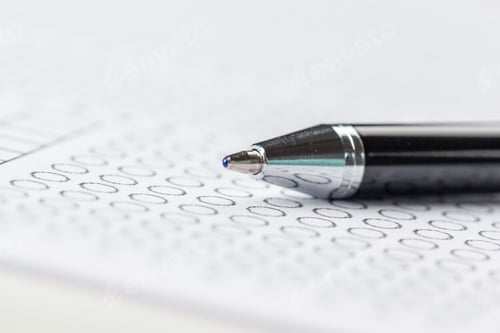 Preview: Black pen placed on a sheet of paper with numbered rows and answers during a test or survey