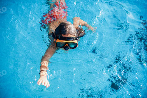 Preview: Sportive kid with goggles swims in pool and pose on camera