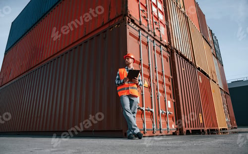 Preview: Digital tablet in hands. Male worker is on the location with containers