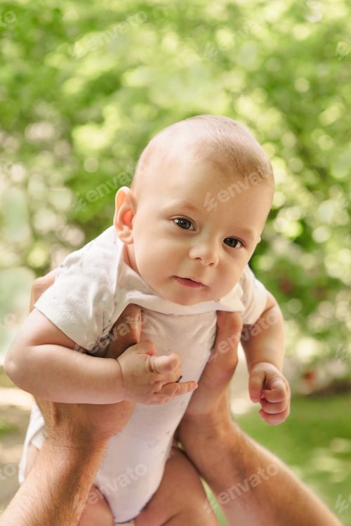 Preview: Baby boy in father's hands filling nice and tender, fatherhood. Cute little son close up over green