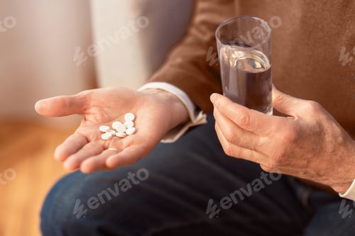 Preview: Unrecognizable Gentleman Holding Pills Sitting On Sofa At Home, Cropped