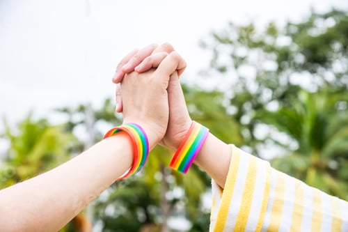 Preview: Two hands holding together wear wrisband Rainbow colored determination in the LGBTQ community