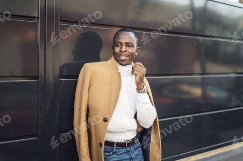 Preview: Shallow focus shot of a stylish handsome smiling African male in a coat posing for the camera