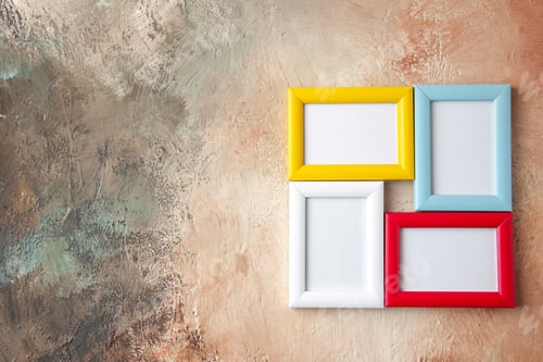 Preview: Close up view of colorful picture frames hanging on nude color wall with free space