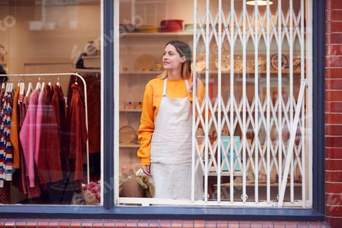 Preview: Female Small Business Owner Pushing Back Security Grill And Opening Shop