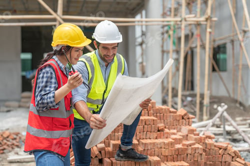 Preview: Asian woman and man civil engineer discuss and look at blueprint in housing estate construction site