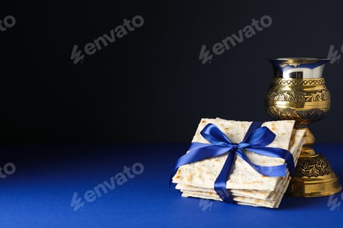 Preview: Matzo with ribbon and cup on dark blue background, space for text