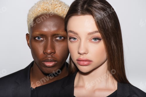 Preview: blonde african american man and pretty brunette woman looking at camera isolated on grey