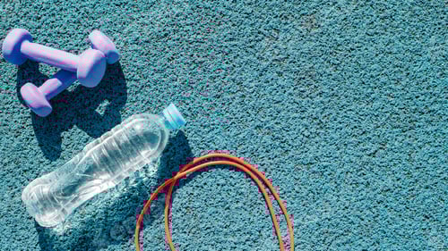 Preview: Sports equipment for training, top view. Skipping rope, dumbbells, bottle of water on rubber