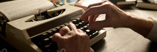 Preview: Senior Caucasian Man Typing on Vintage Typewriter in Warm Indoor Lighting