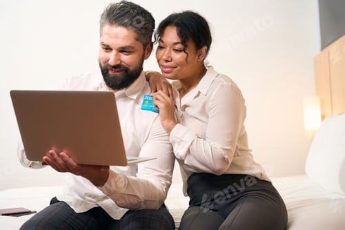 Preview: Joyous couple making online payment in hotel room