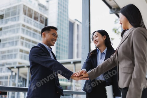 Preview: Business team joining hands, celebrating success in urban setting